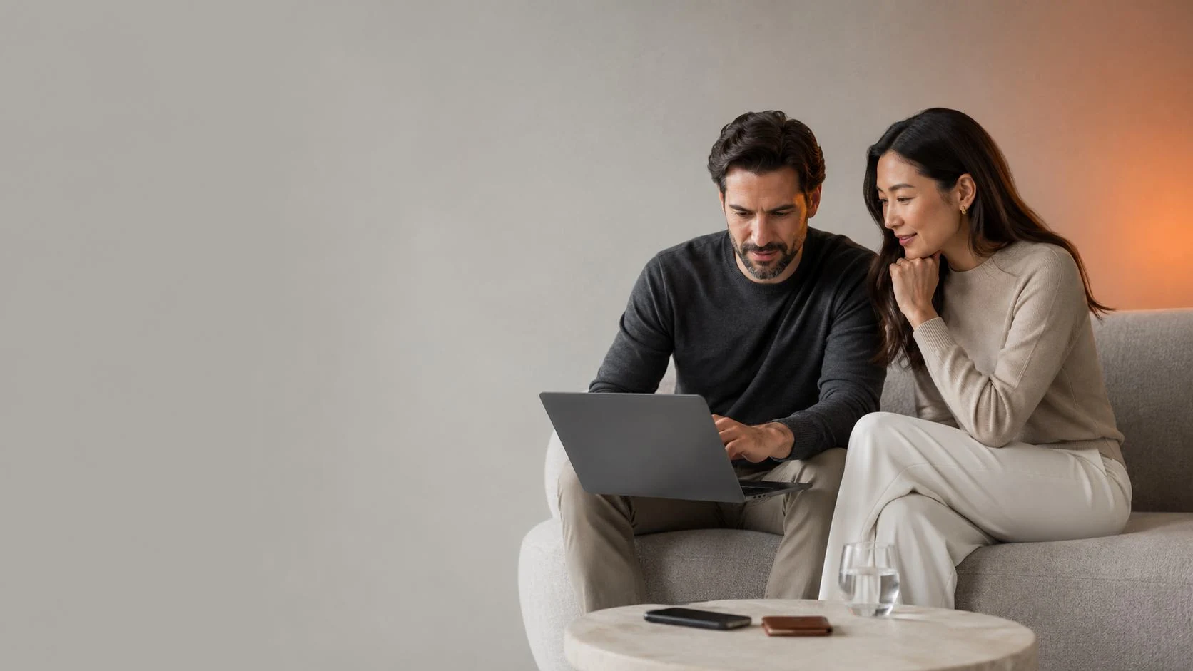Two people reviewing an account together on a sofa